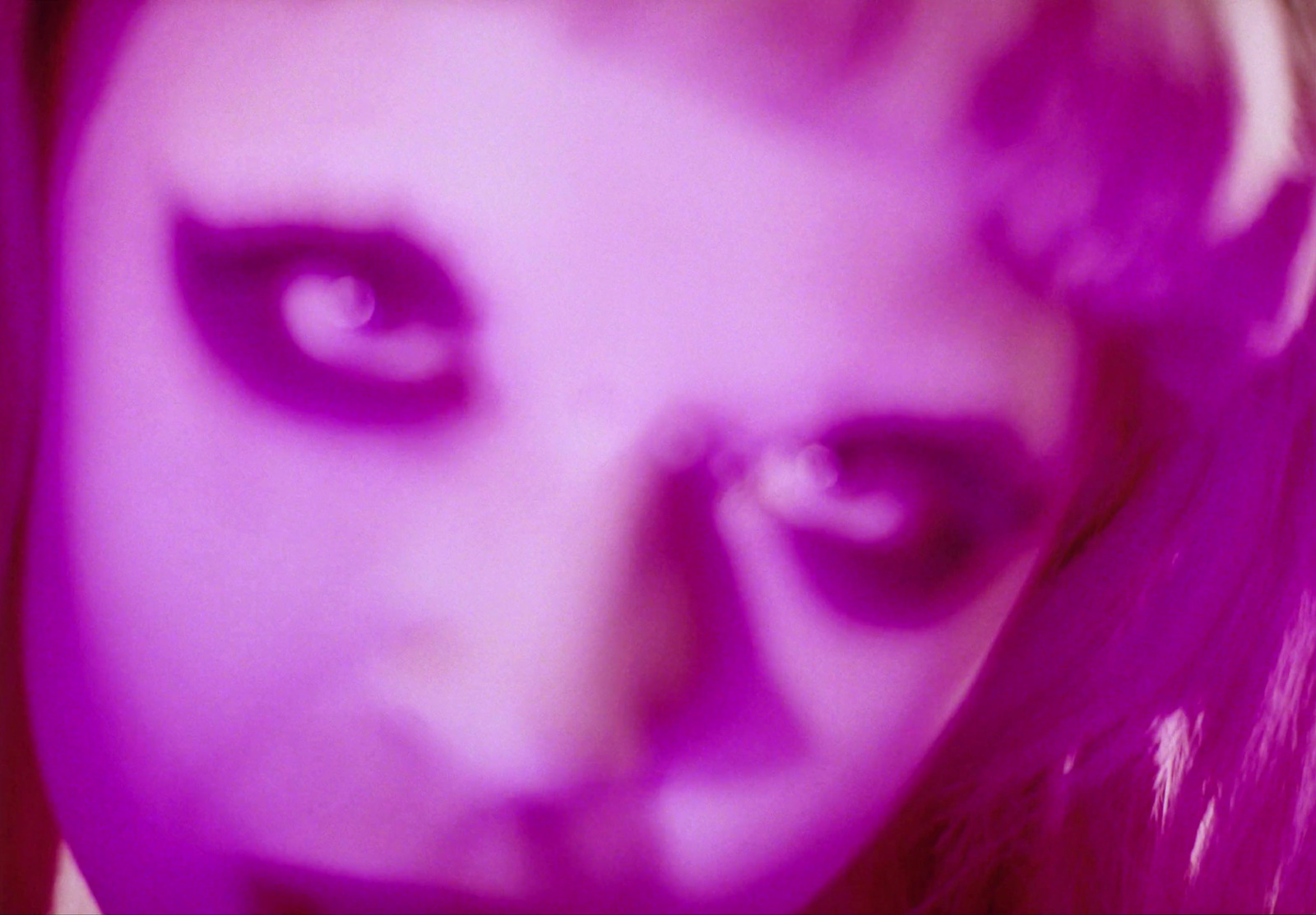 a close up of a woman's face with purple light