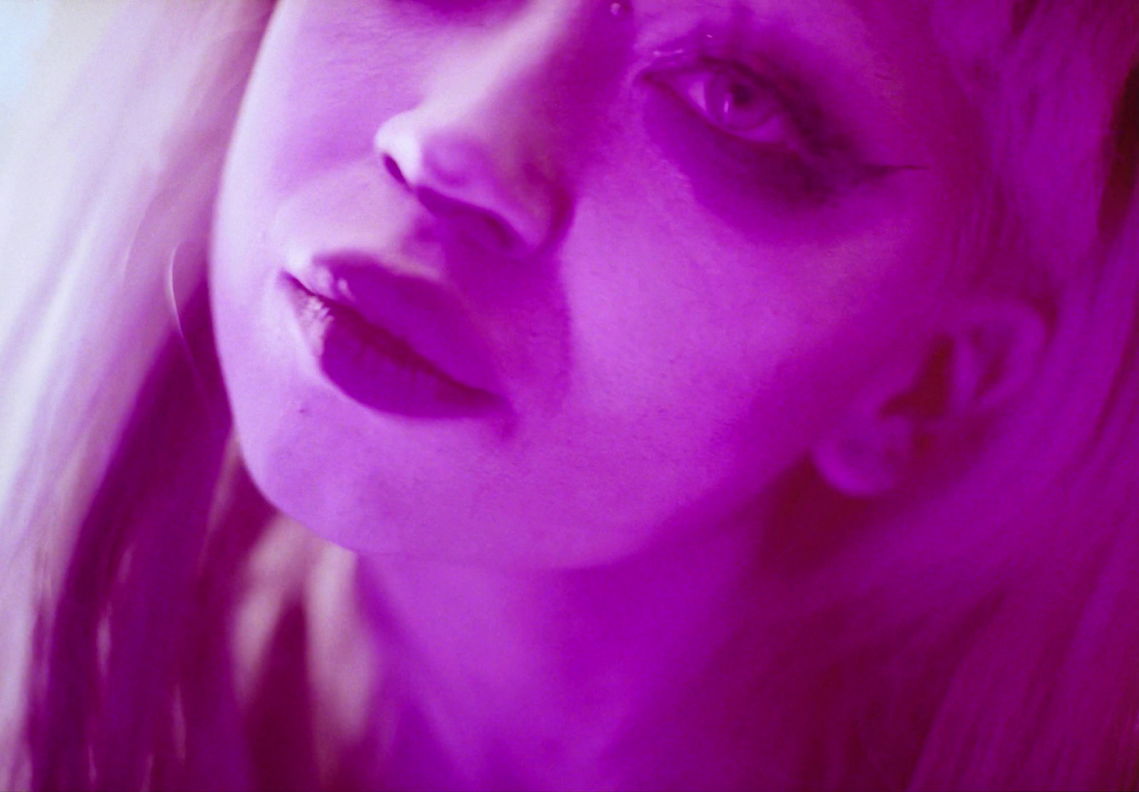 a close up of a woman's face with purple light