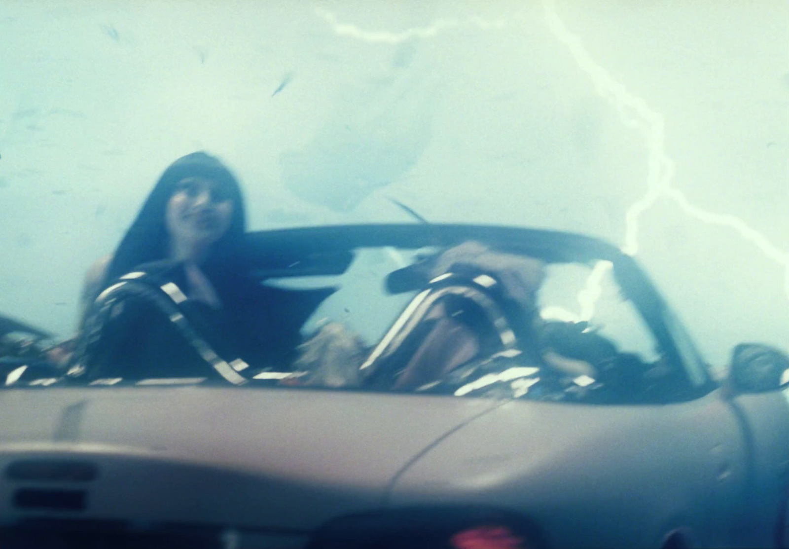 a woman sitting in a car with a lightning bolt in the background