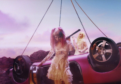 a woman in a dress holding a baseball bat next to a car