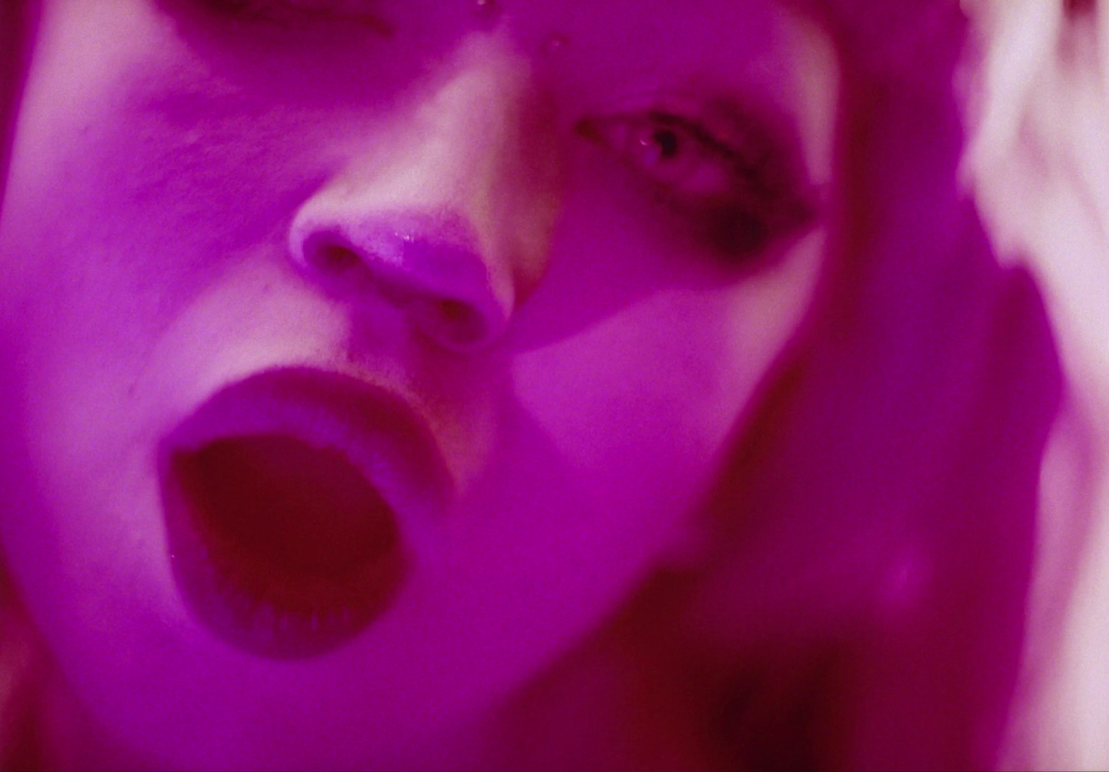 a close up of a woman's face with purple light