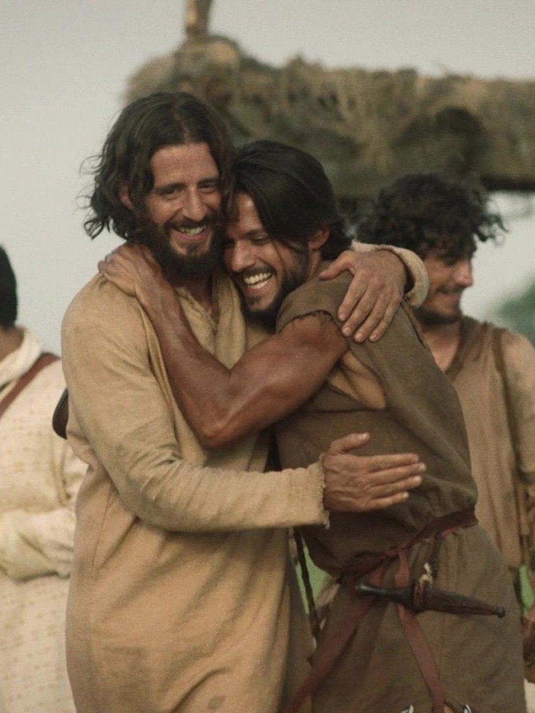 two men hugging each other in front of a group of people