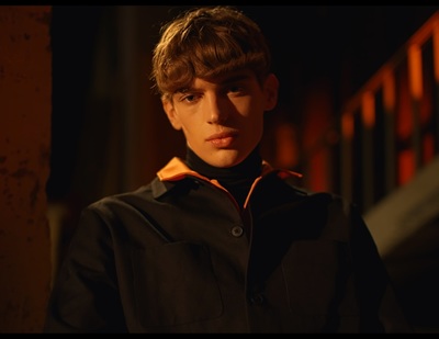 a young man in a black and orange jacket