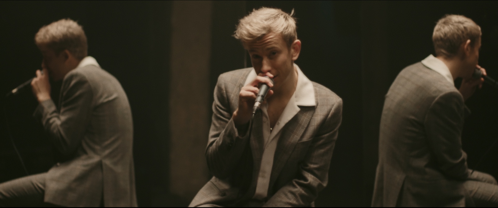 a man in a suit sitting on a chair with a microphone