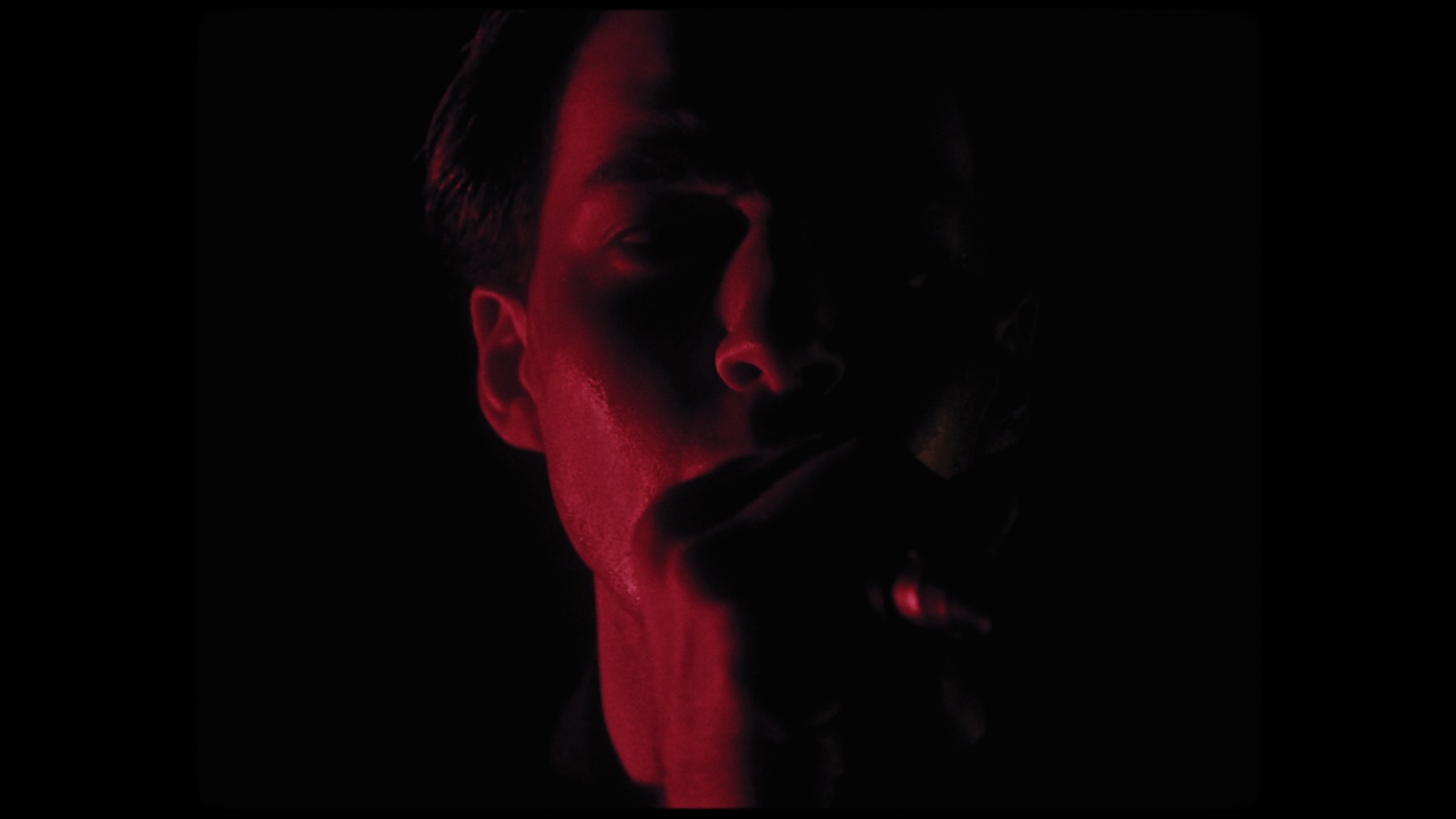 a man with his hand on his mouth in the dark