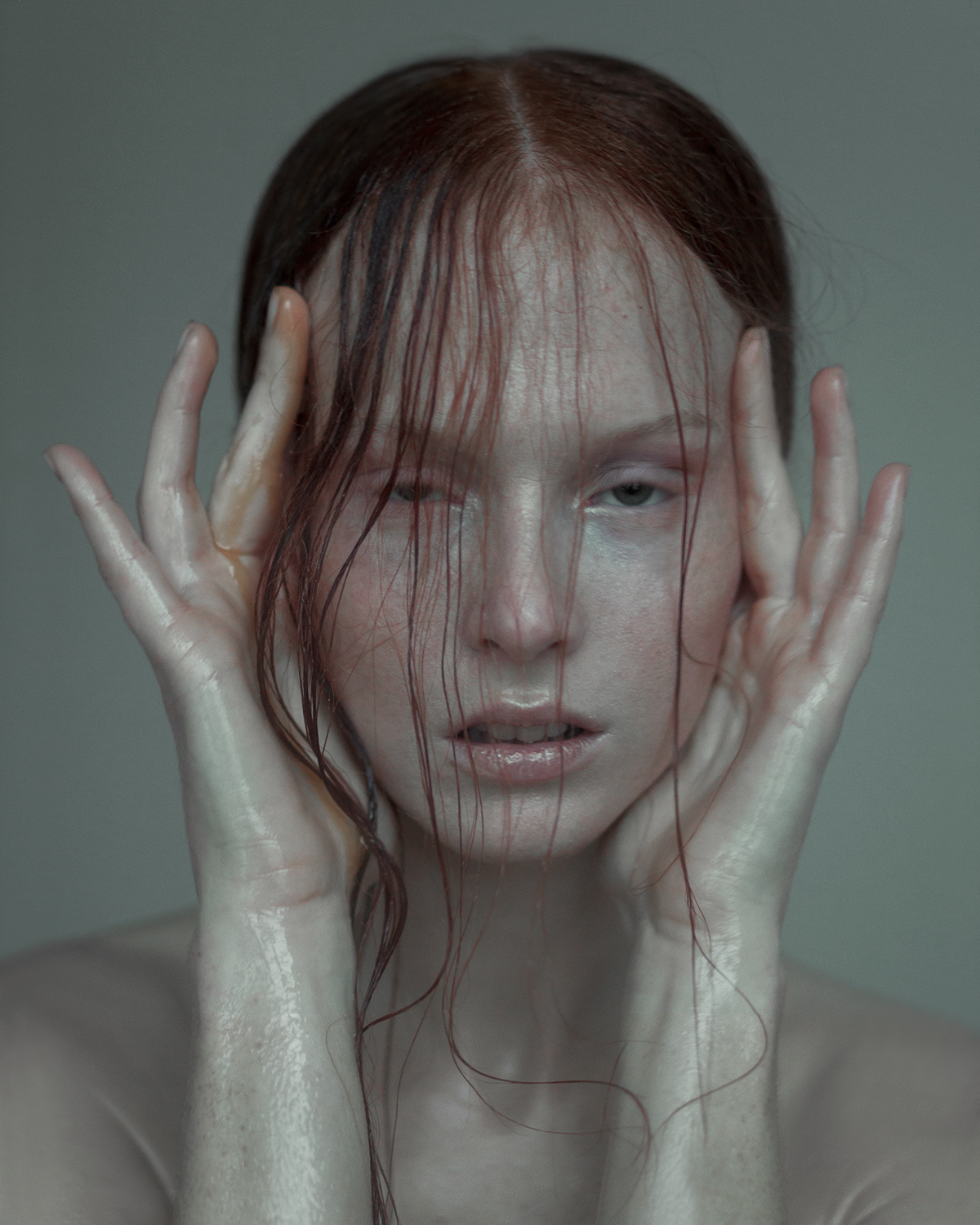 a woman with red hair holding her hands to her face