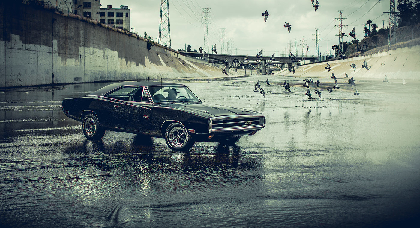 a black muscle car parked on a wet street