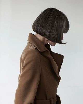 a woman in a brown coat with a short haircut