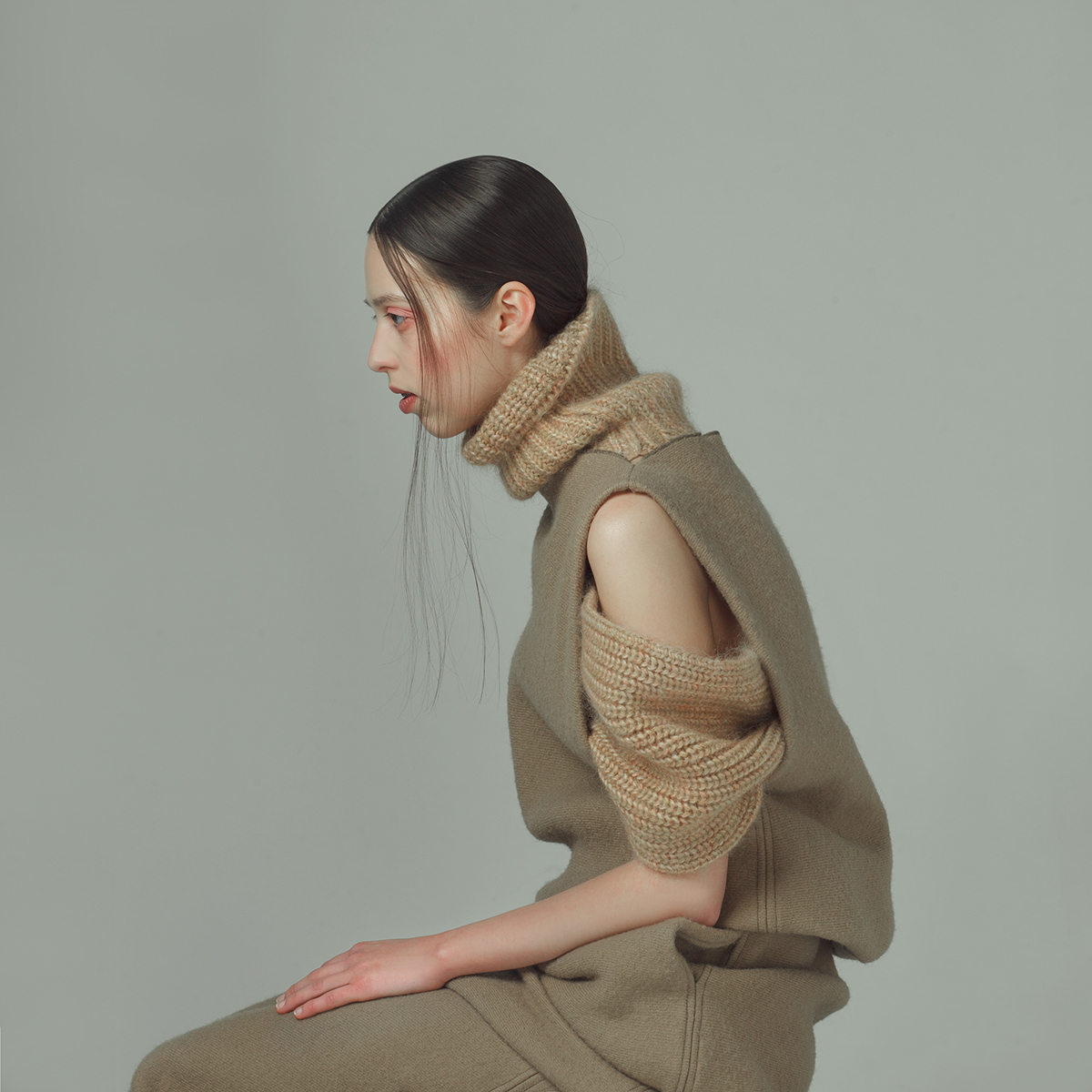 a woman sitting on a stool with a scarf around her neck