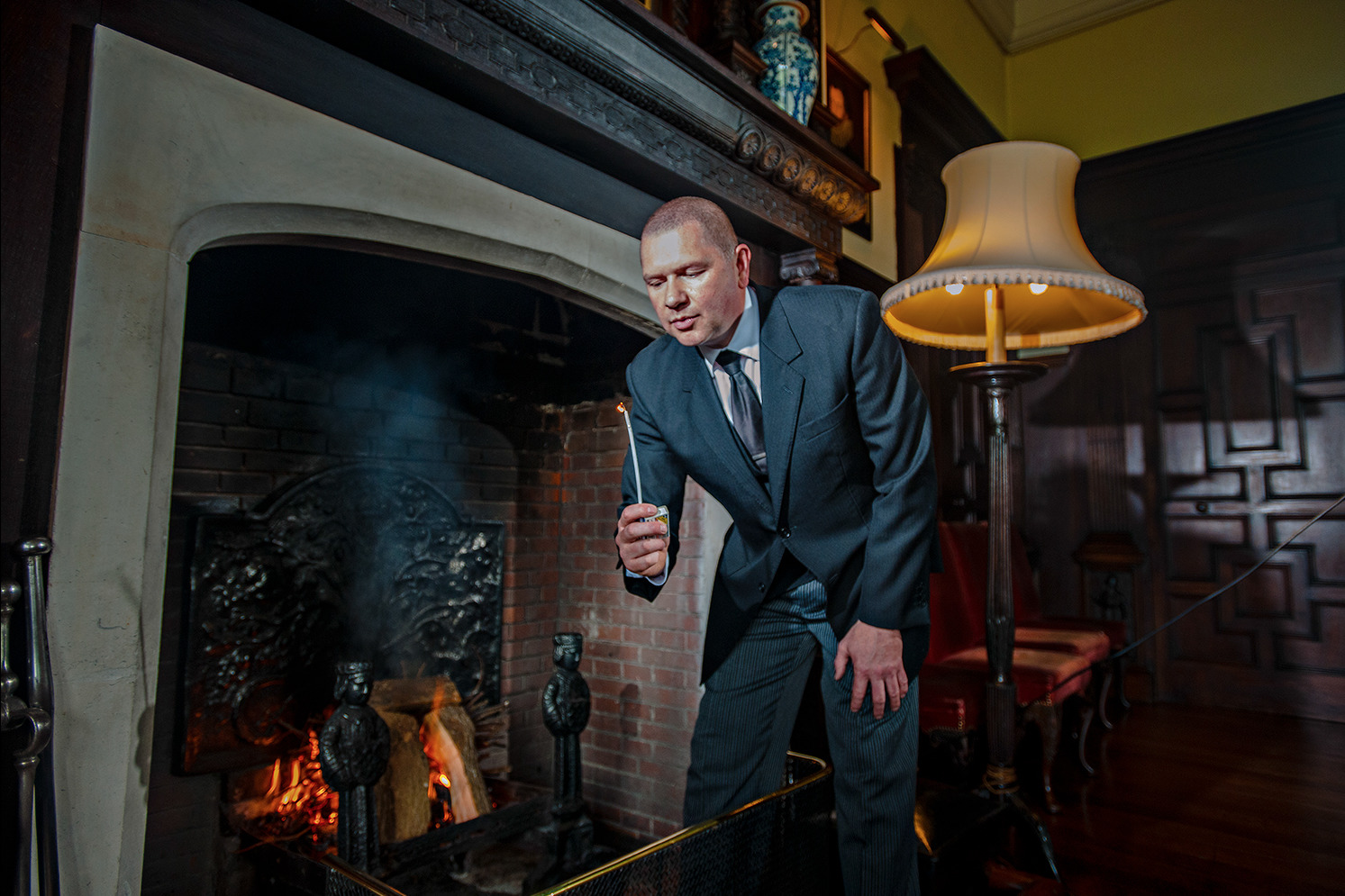 a man in a suit and tie standing in front of a fireplace