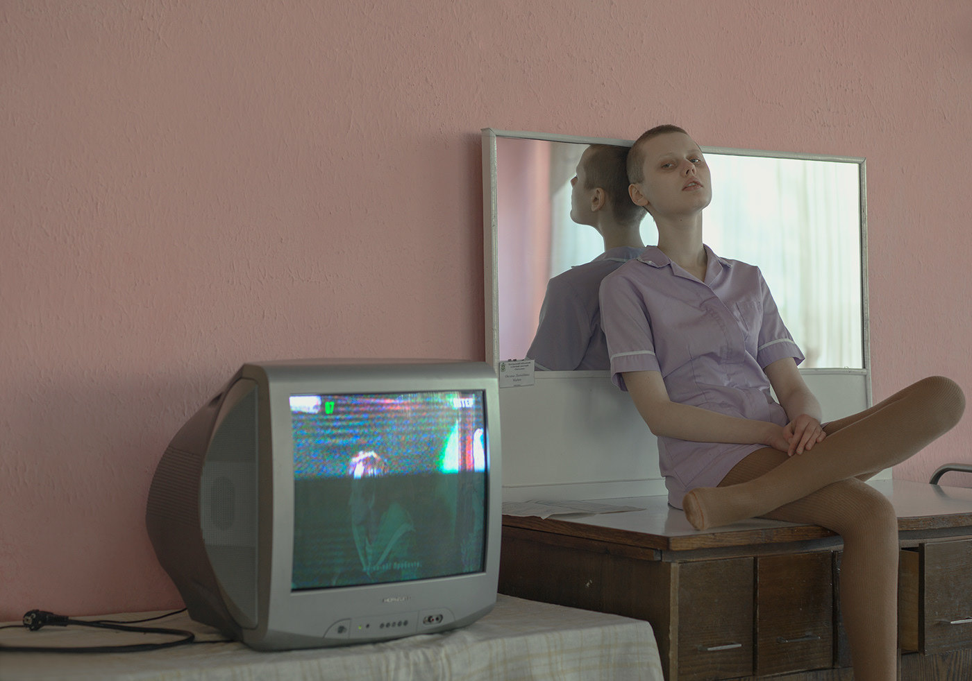 a woman sitting on a desk in front of a tv