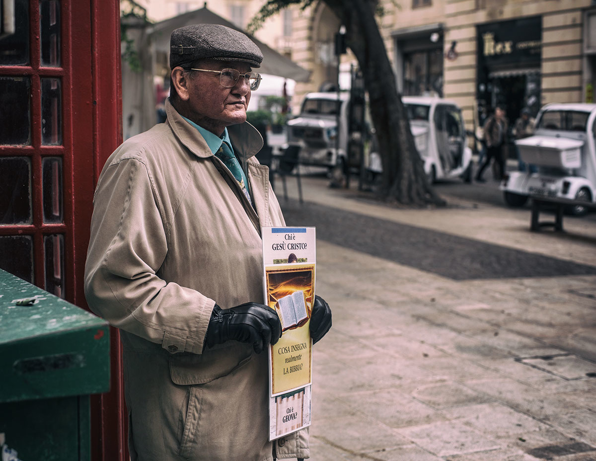 a man standing on a sidewalk holding a newspaper