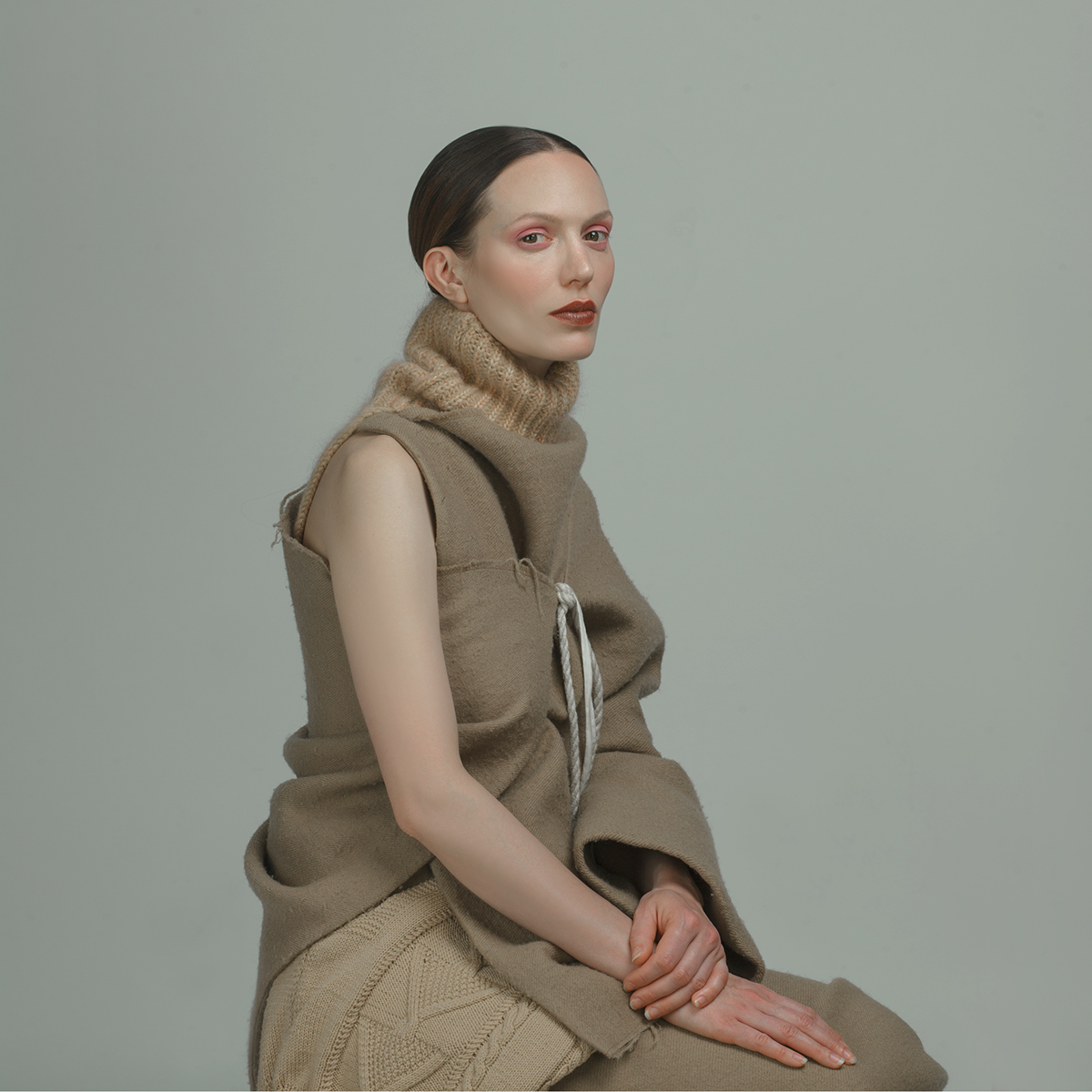 a woman sitting on a stool with a scarf around her neck