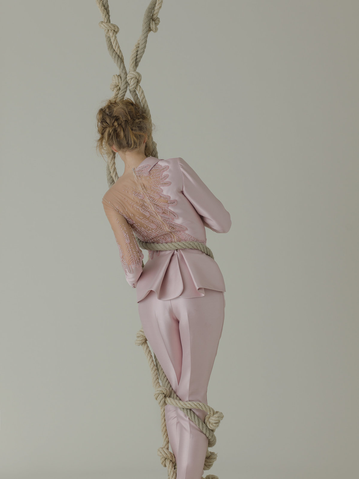 a woman in a pink dress is hanging on a rope