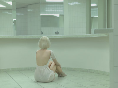 a woman sitting on the floor in a bathroom