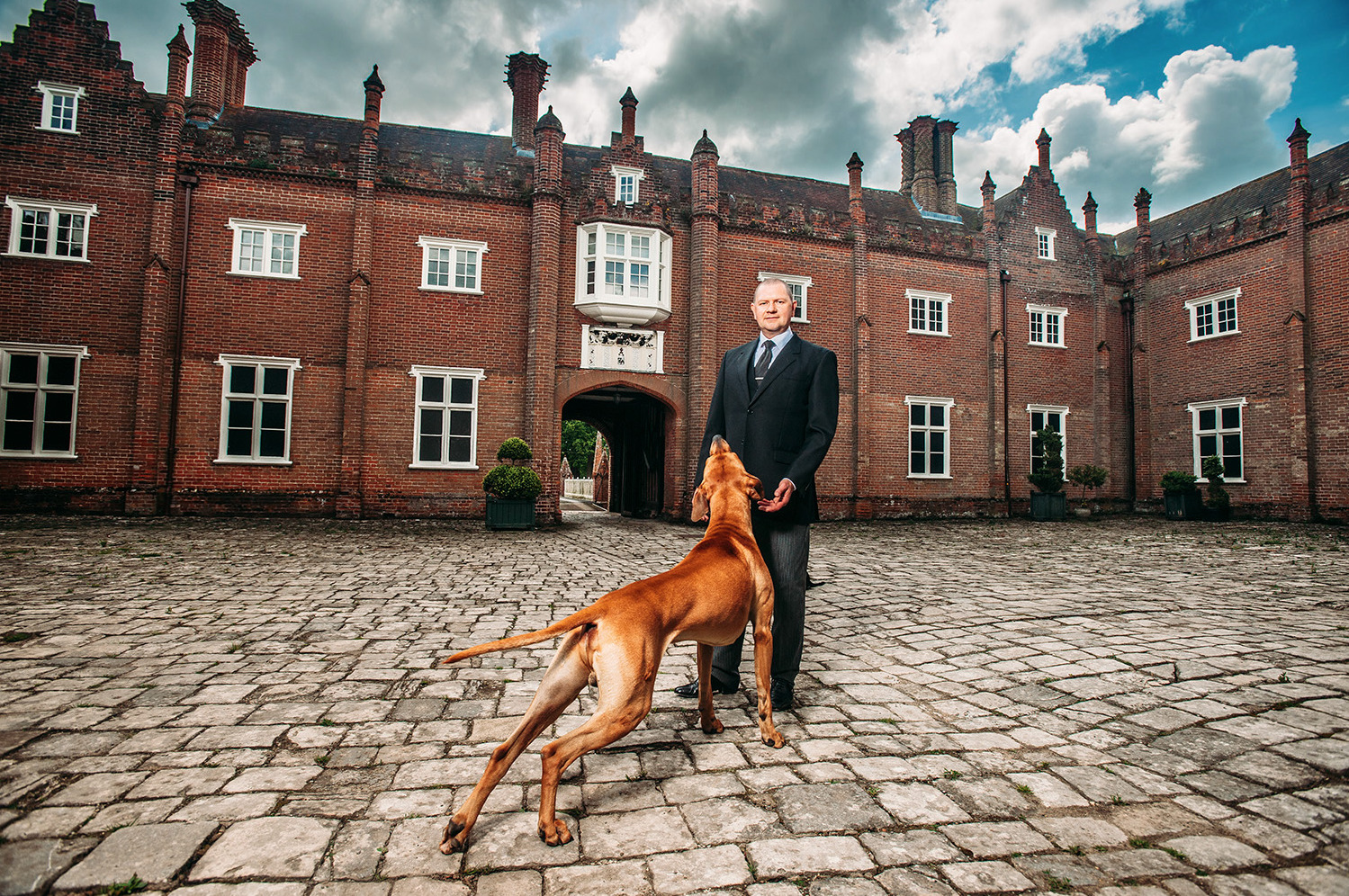 a man in a suit standing next to a brown dog