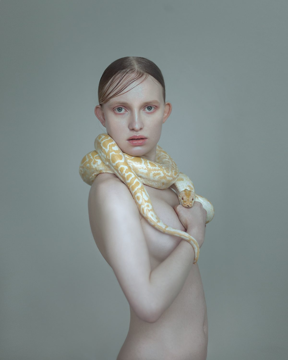 a nude woman with a large snake around her neck