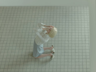 a woman standing on a tiled floor with her hands on her head