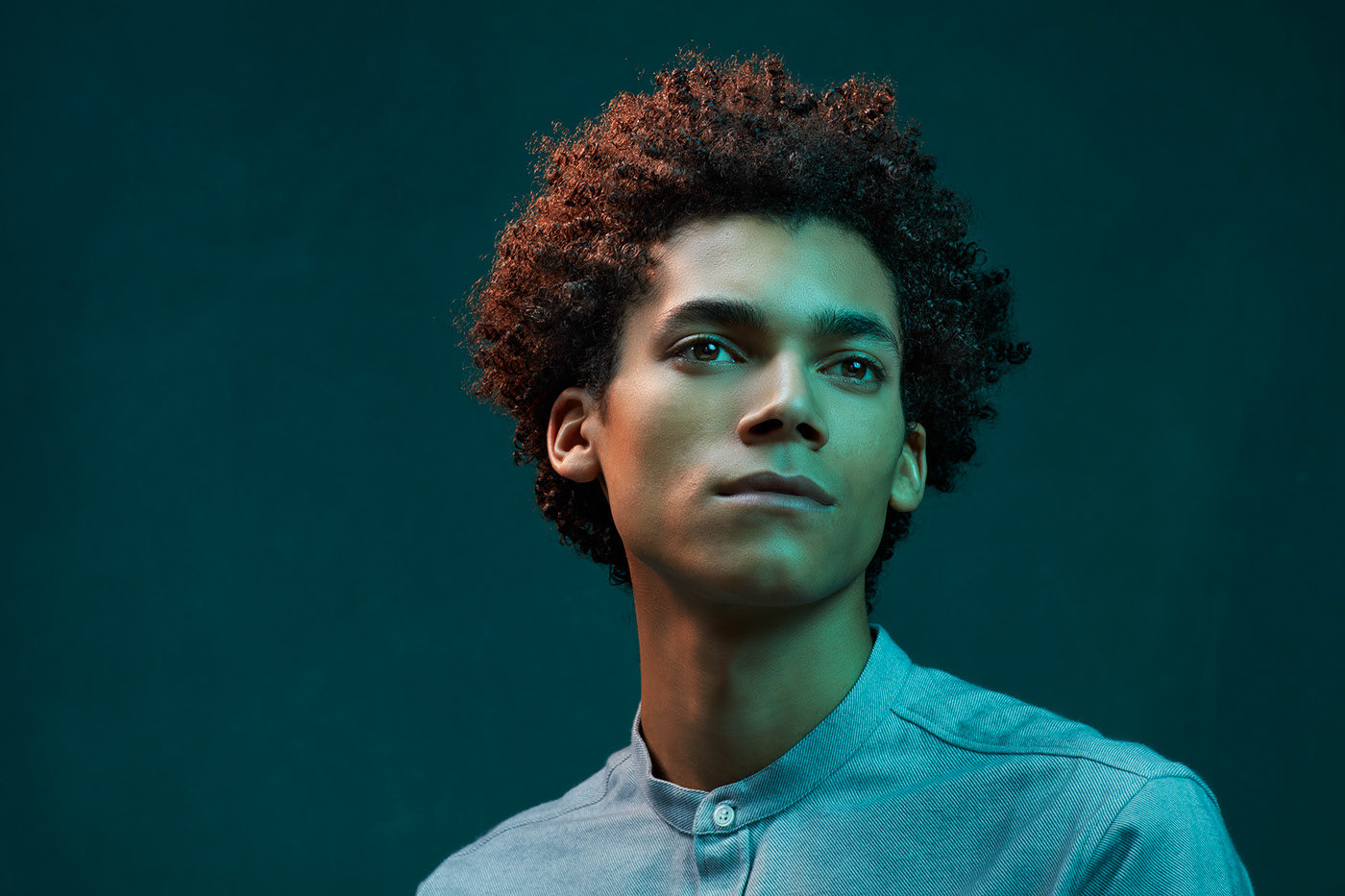 a man with curly hair wearing a blue shirt