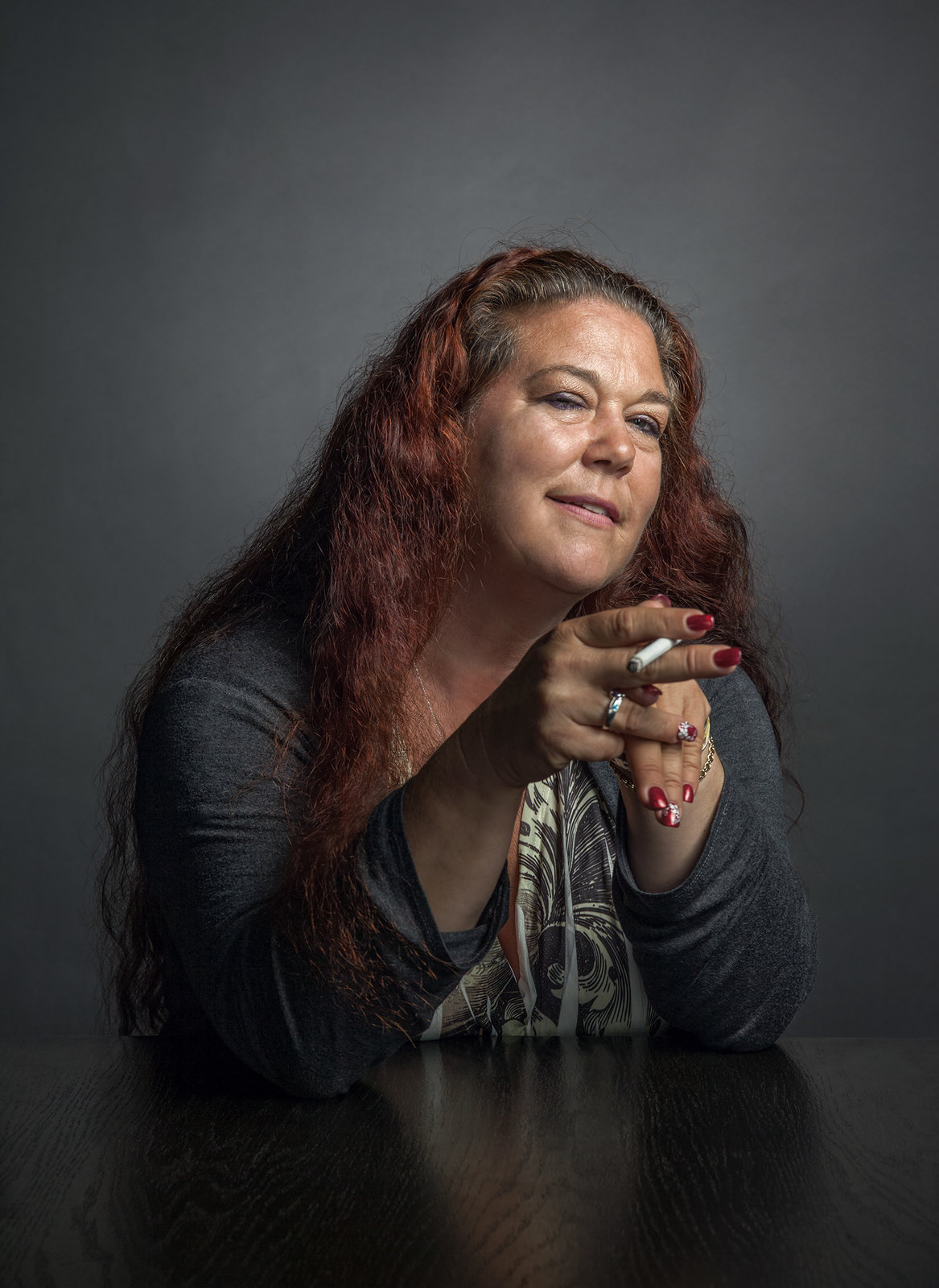 a woman sitting at a table with a cigarette in her hand