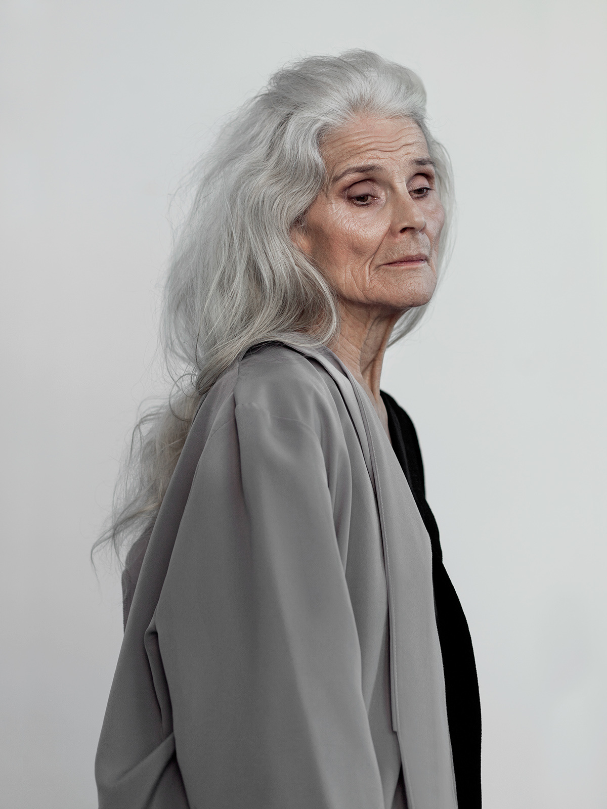 a woman with white hair and a gray jacket