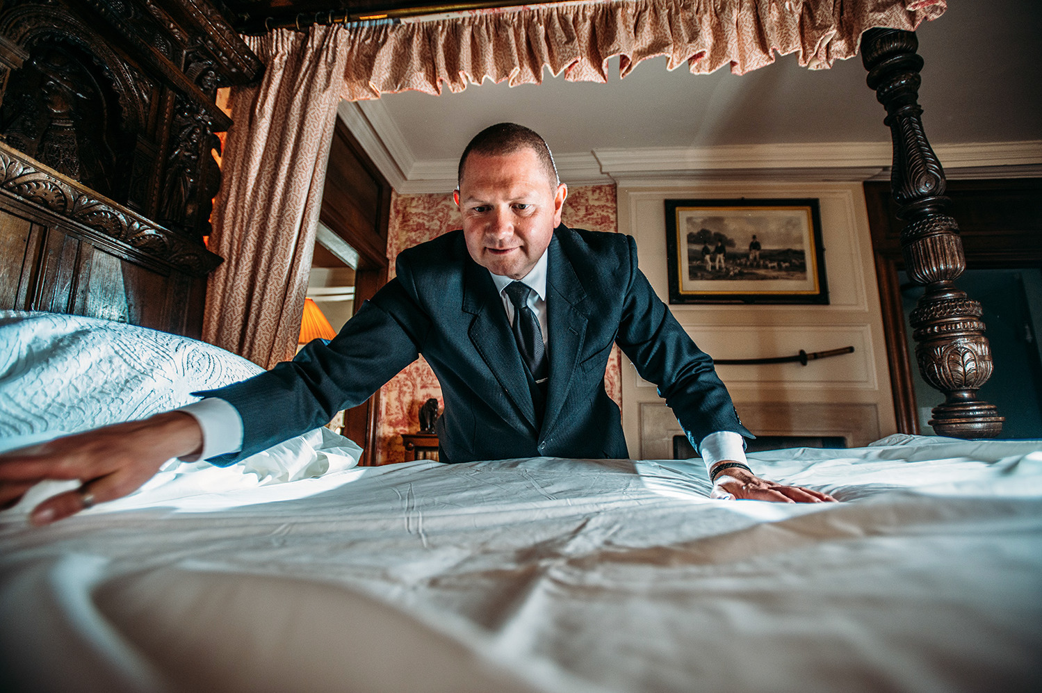 a man in a suit leaning over a bed