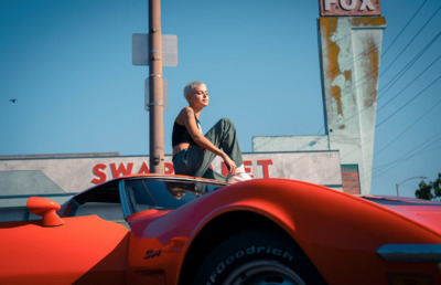 a man sitting on top of a red sports car