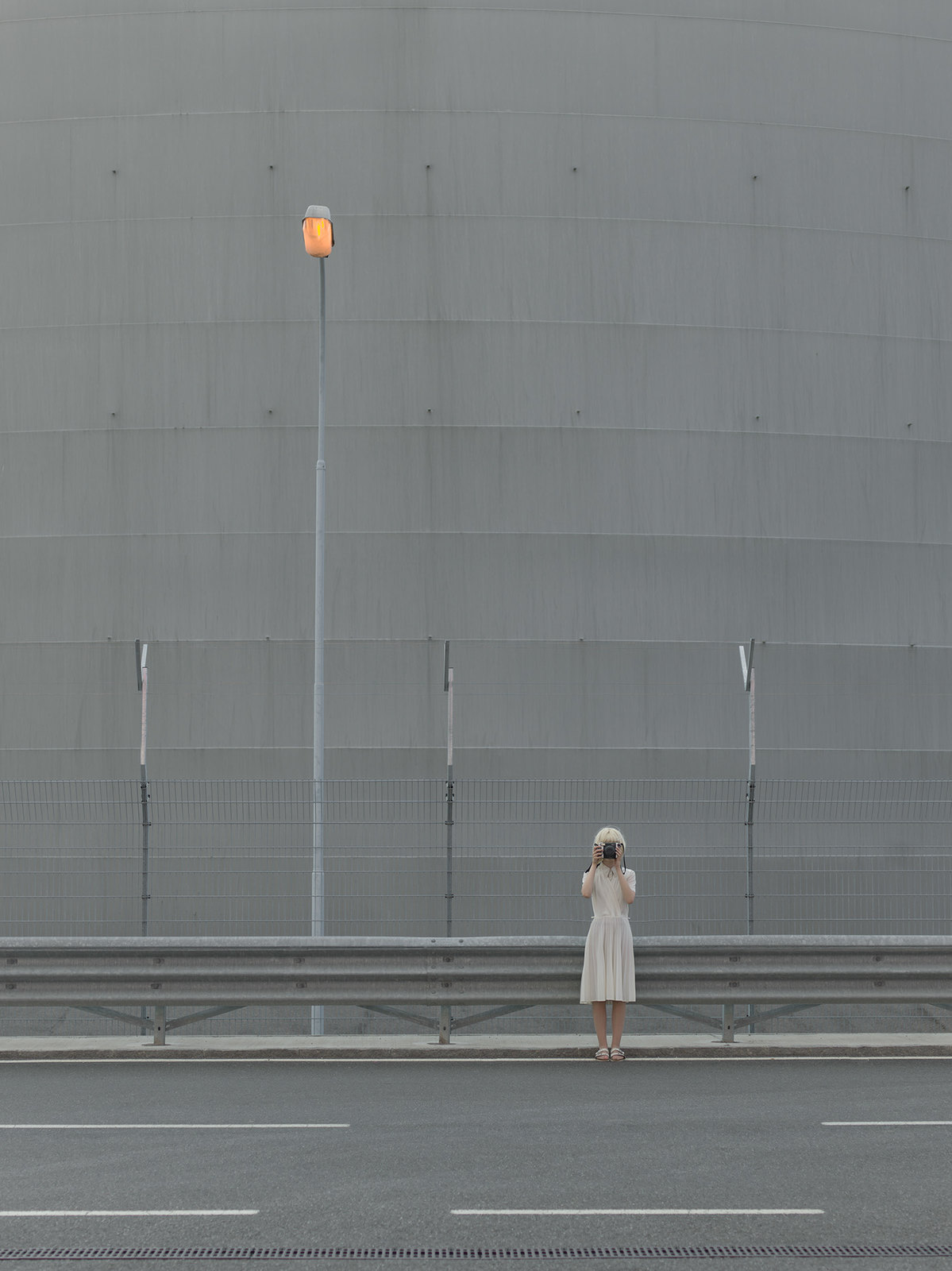 a woman in a white dress is standing on the side of the road