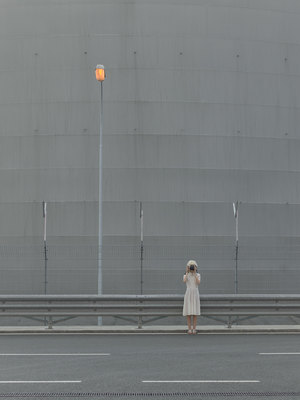 a woman in a white dress is standing on the side of the road