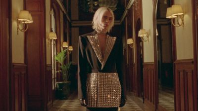 a woman standing in a hallway wearing a gold and black outfit