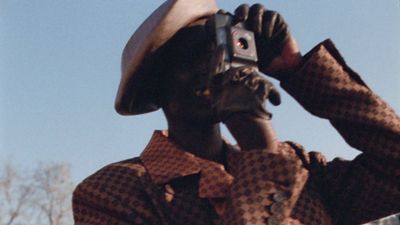 a man wearing a hat and holding a camera up to his face