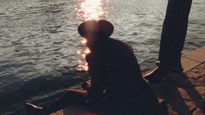 a man sitting on a dock next to a body of water