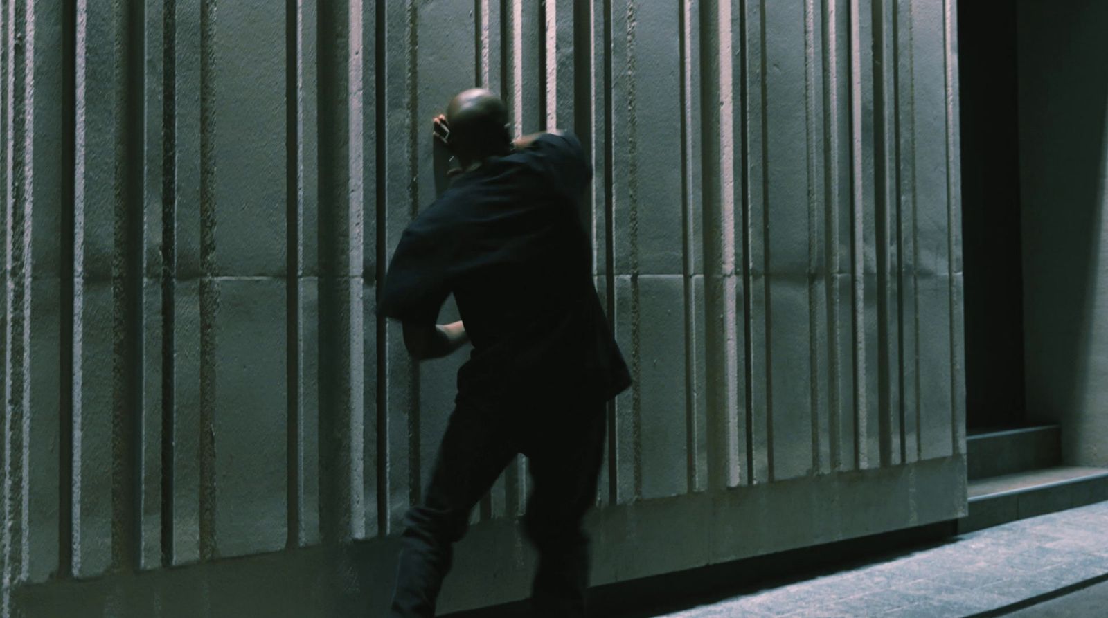 a man leaning against a wall talking on a cell phone