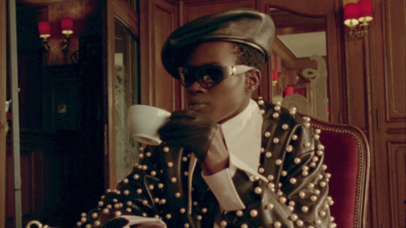 a man sitting in a chair drinking from a cup