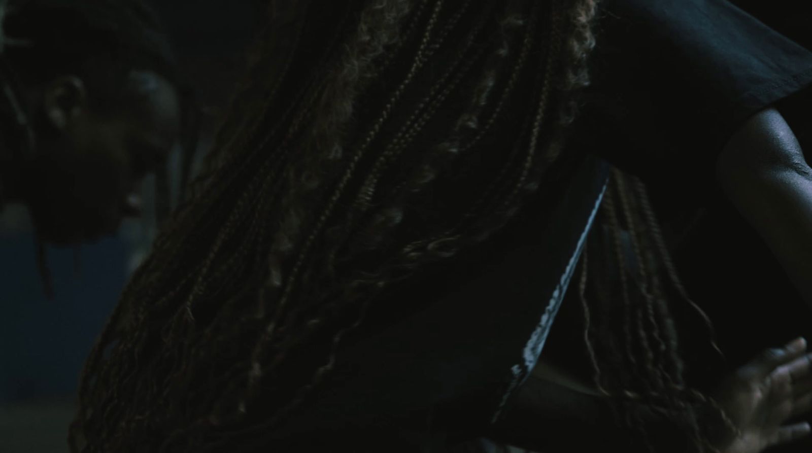 a man with dreadlocks standing in a dark room