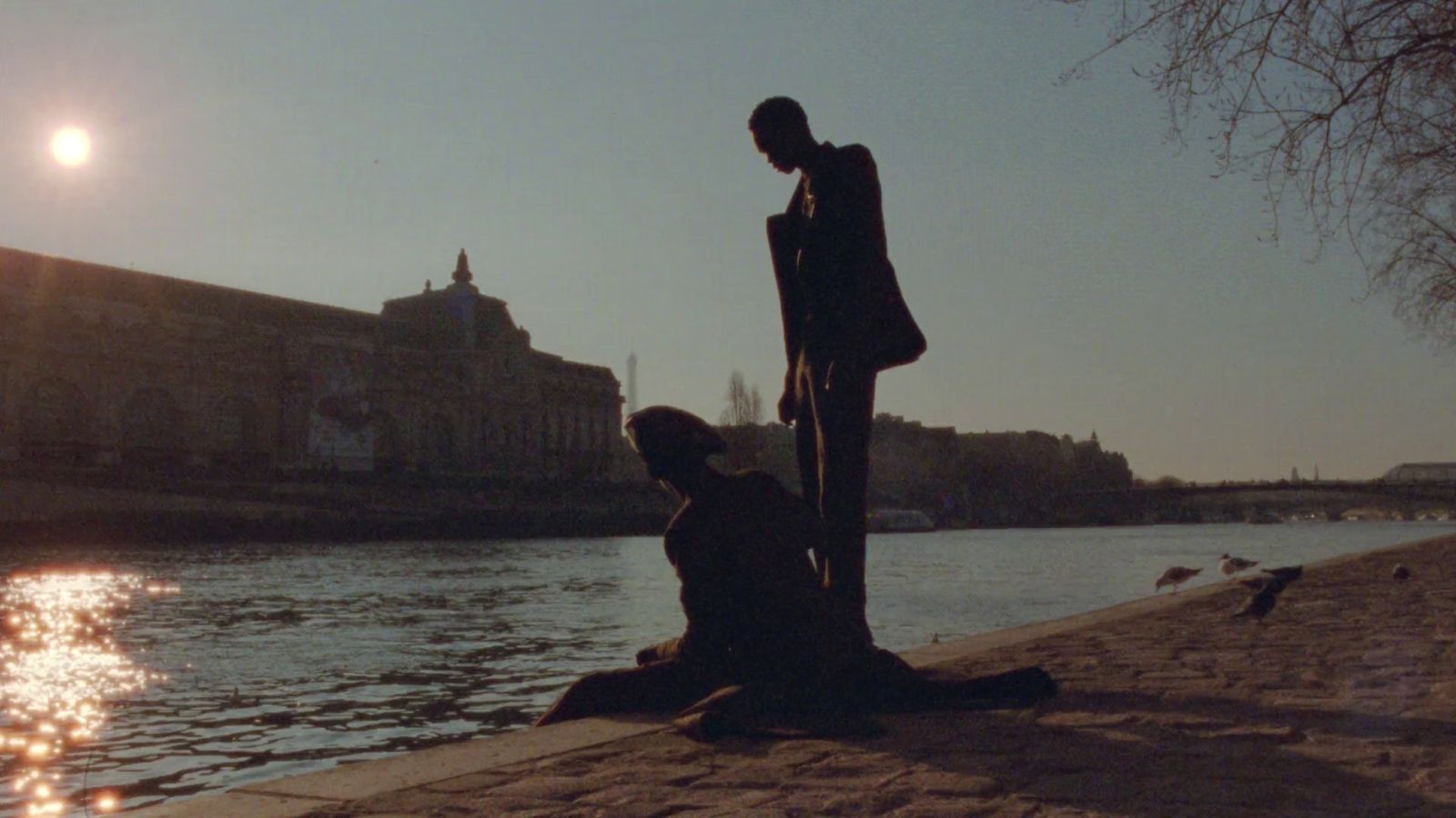 a couple of people sitting next to a body of water