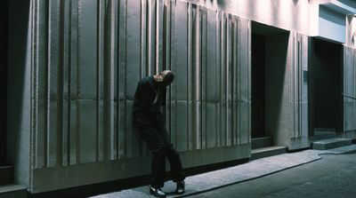 a man leaning against a wall on the side of a building