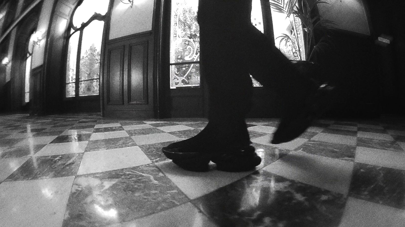 a black and white photo of a person's legs and shoes