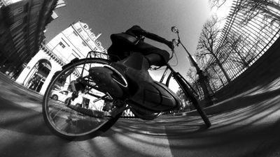 a man riding a bike down a street next to tall buildings