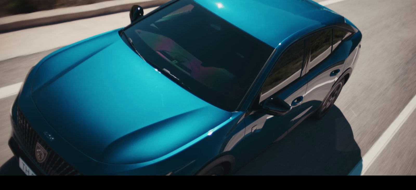 a blue car driving down a road next to a forest