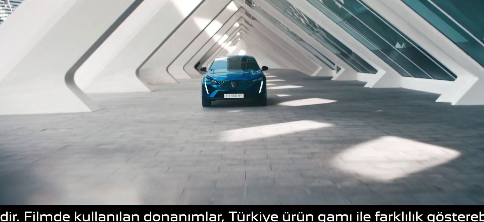 a blue car driving down a street next to tall buildings