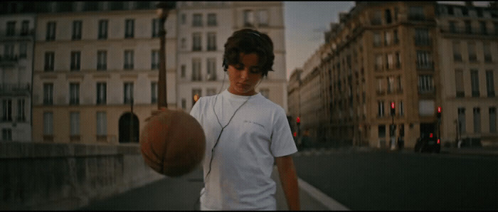 a young man holding a basketball on a city street