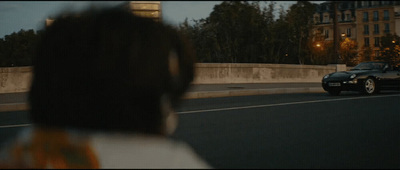 a car driving down a street next to a bridge