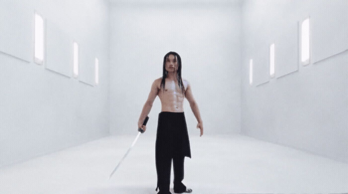 a man with long hair holding a sword in a white room