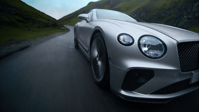 a silver sports car driving down a mountain road