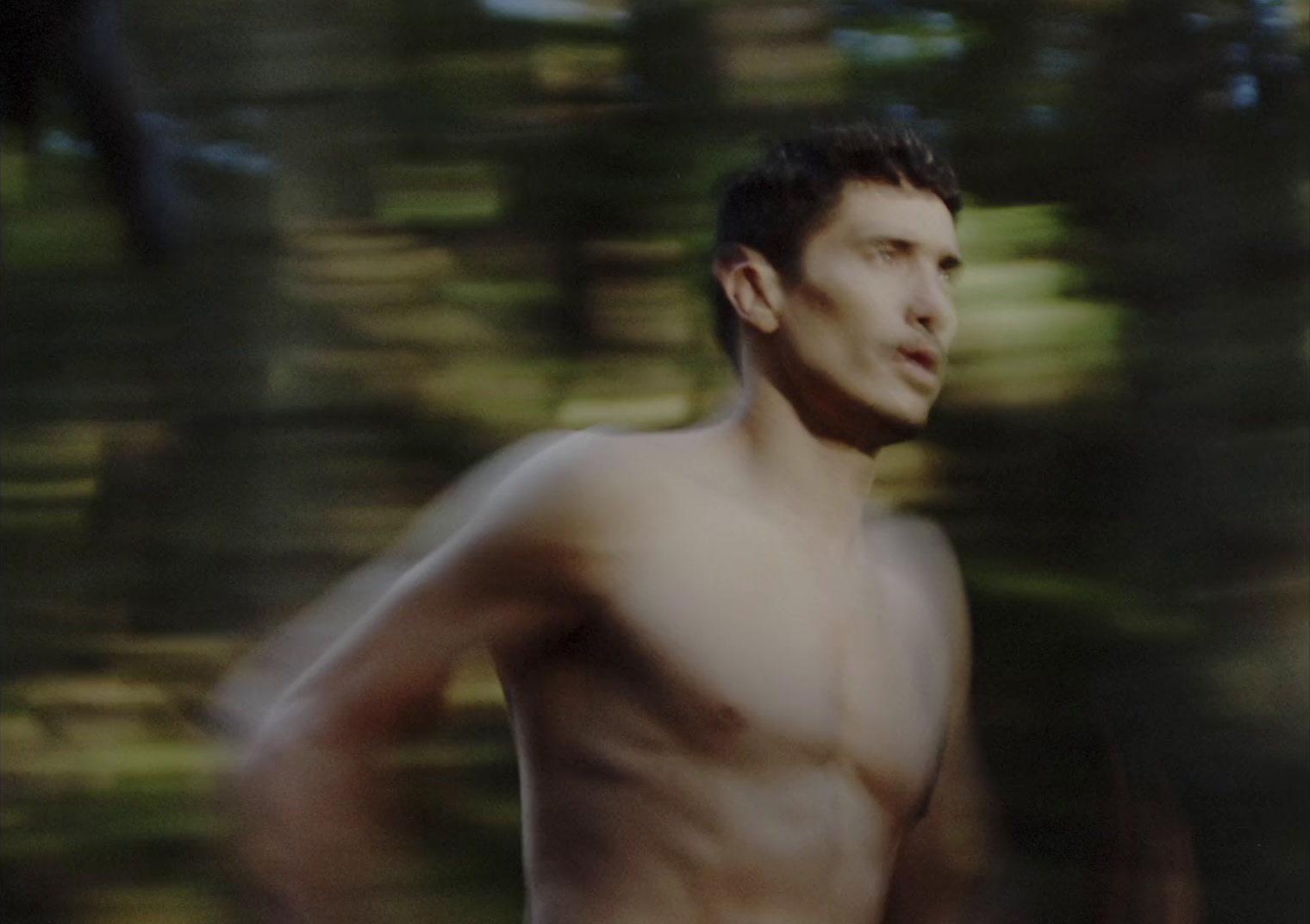 a man without a shirt is running in the woods