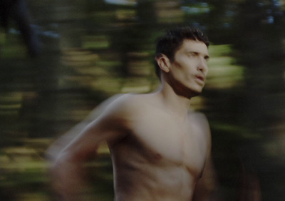 a man without a shirt is running in the woods