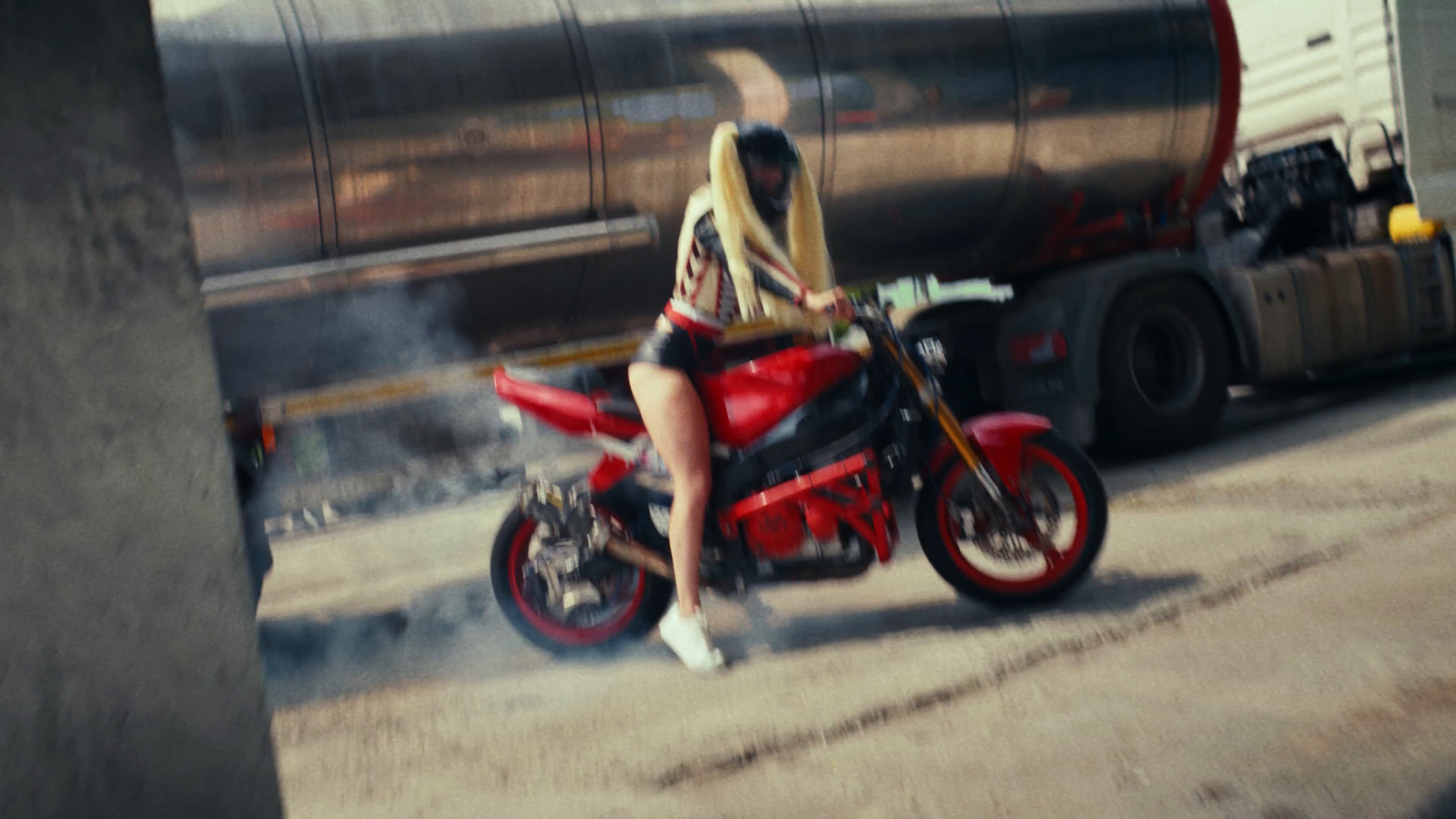 a woman riding a red motorcycle down a street