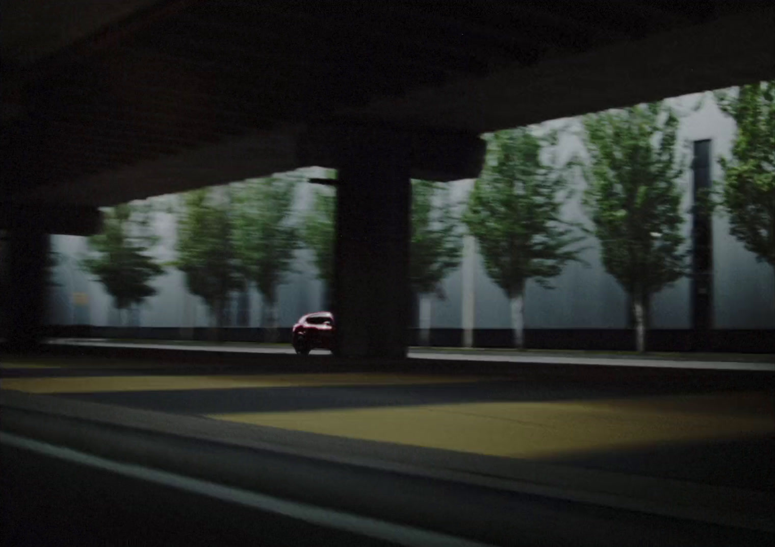 a car driving down a street under a bridge