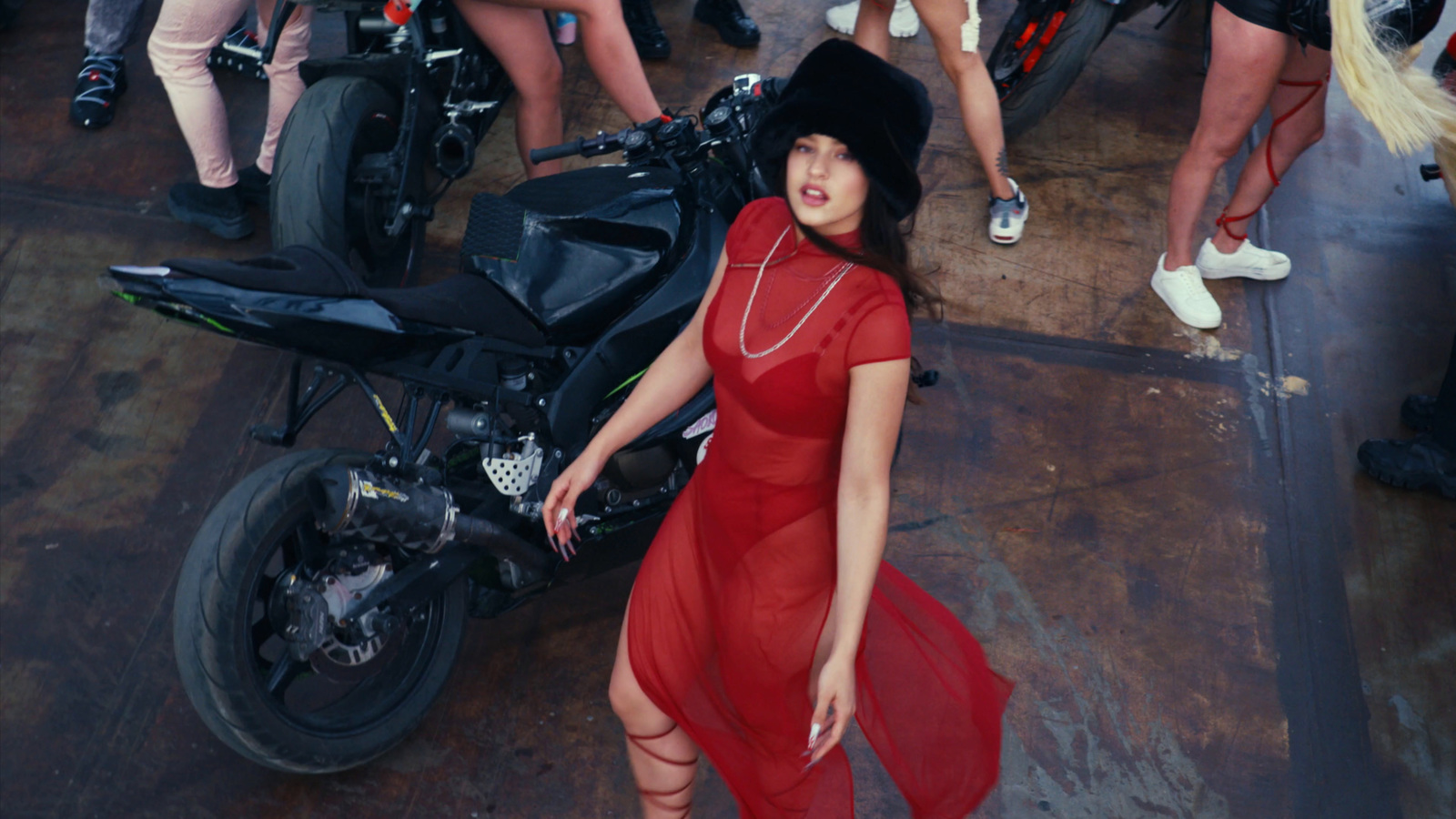 a woman in a red dress standing next to a motorcycle